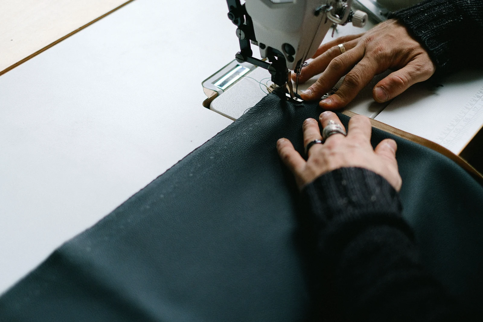 Hands stitching fabric on a sewing machine — representative production photograph
